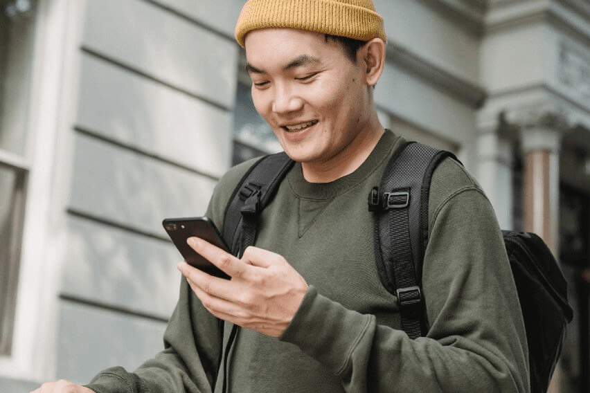 Man on street looking at phone smiling